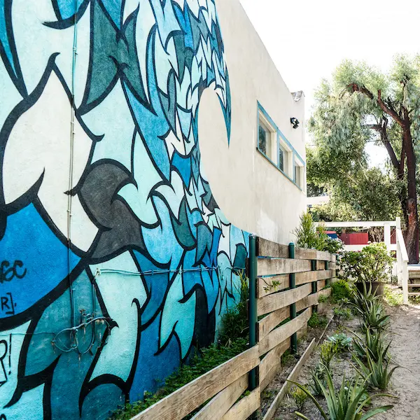 Blue-toned mural of stylized ocean waves on the side of a building near the Venice Canals