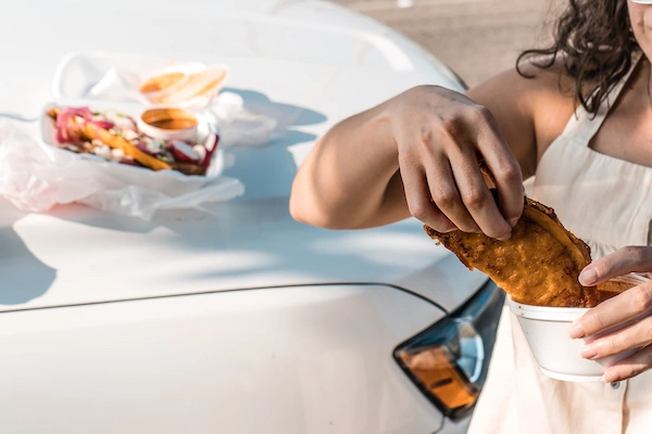dipping a taco in a side of consome and a hood of a truck with take out