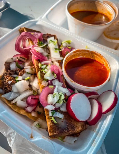 bone marrow covered in picked onions, side of consome and a taco