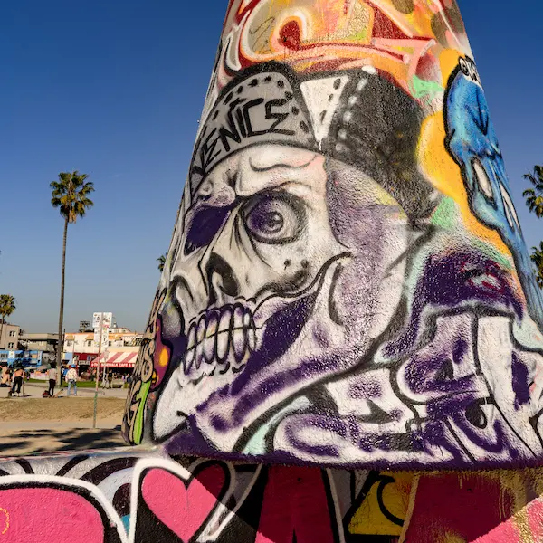 Close-up of a Venice Beach graffiti-covered cone featuring a skull wearing a beanie with the word "Venice."