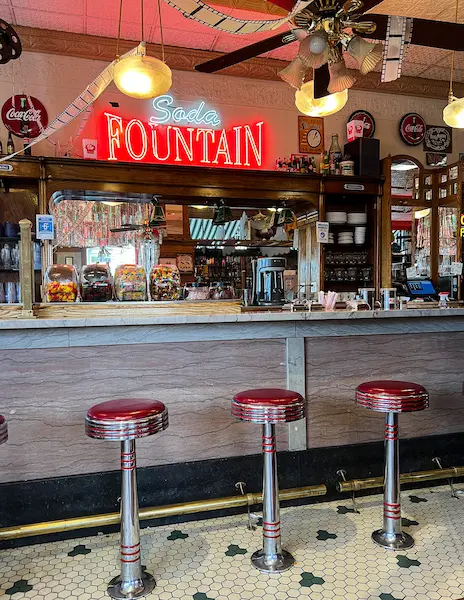 stool with red leather at an ice cream counter and glowing soda fountain shop on wall