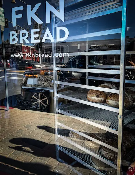 fkn bread sign on the window and a cart of crusty breads