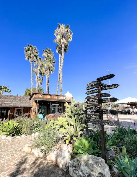 directional arrows, wooden structure and palm trees against blue sky