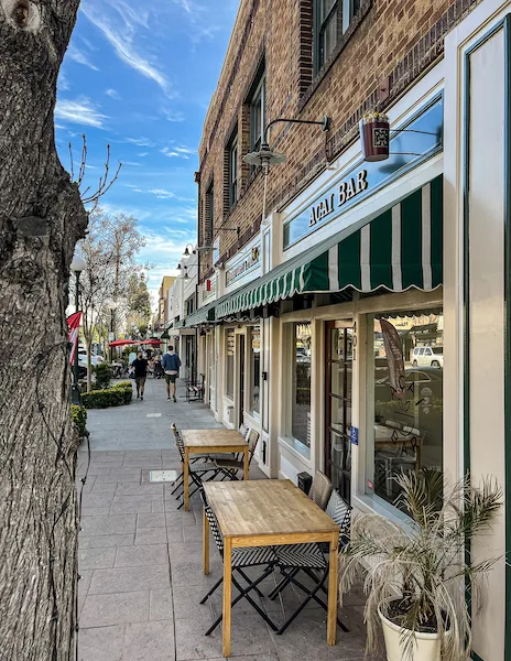 Sidewalk view of shops and cafés in Old Town Monrovia with outdoor seating and striped awnings.