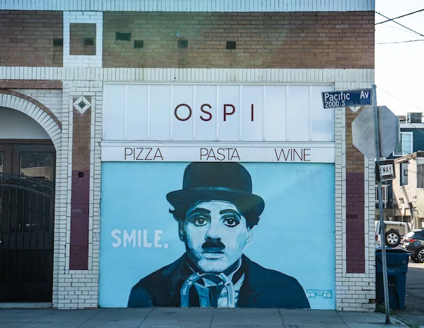 Mural of Charlie Chaplin with the word "SMILE." painted on a storefront wall at the corner of Pacific Avenue in Venice Beach.