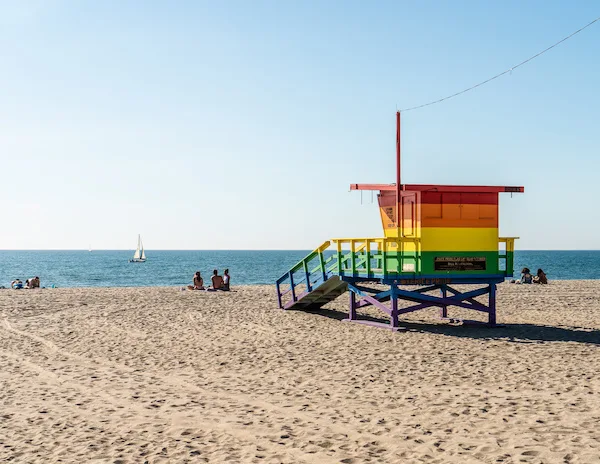 a lifeguard tower with rainbow colors facing the ocean