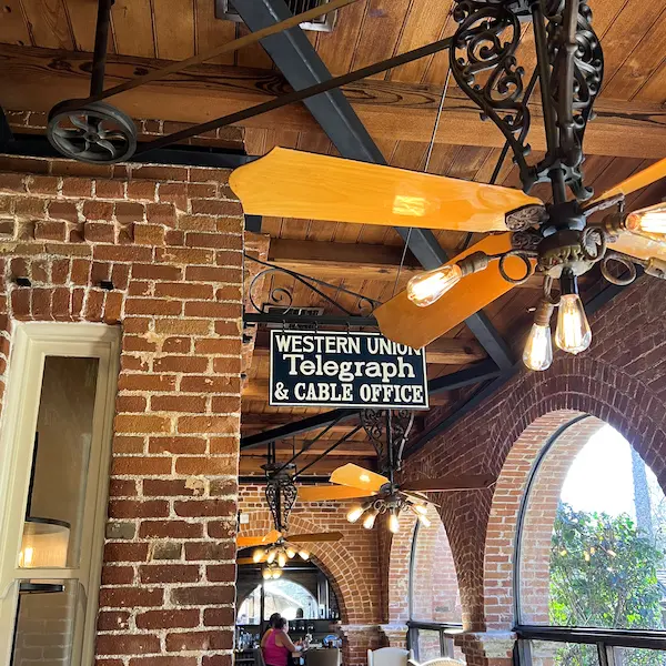 An old Western Union Telegraph & Cable Office sign hanging inside Trevor on the Tracks, with brick walls, fans, and vintage lighting.