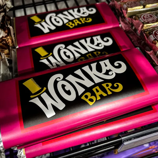 Close-up of bright pink Wonka Bars on a shelf at Sweet Ethans candy store.
