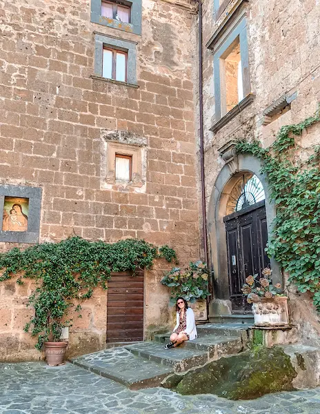 kathy sitting inside the main square of civita di bangoregio