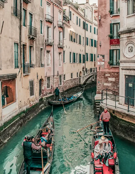 people taking gondola rides in the narrow canals of venice italy