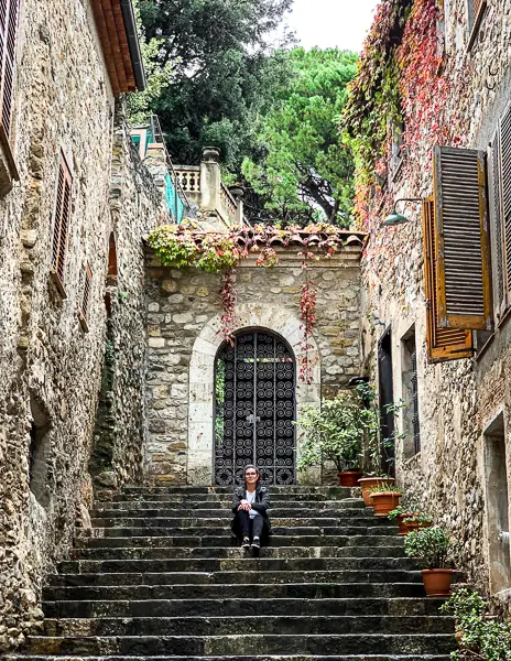 woman sits in the middle of the steps leading to an iron gate 