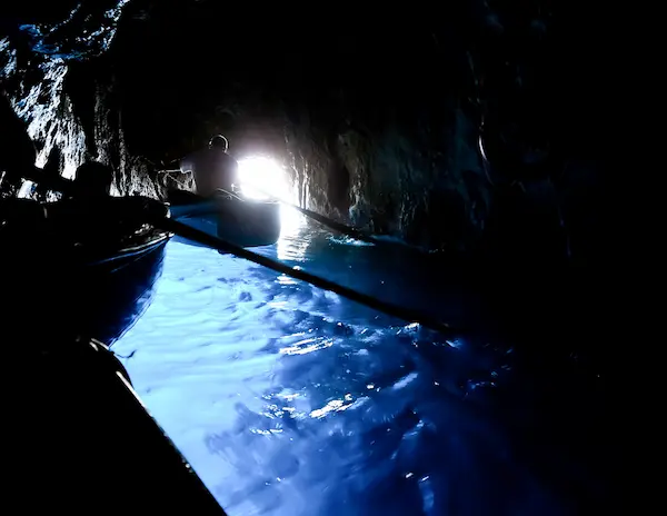 dark shadows of boats in a cave over glowing blue water