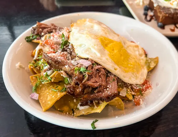 fried eggs over carnitas and tortilla chips