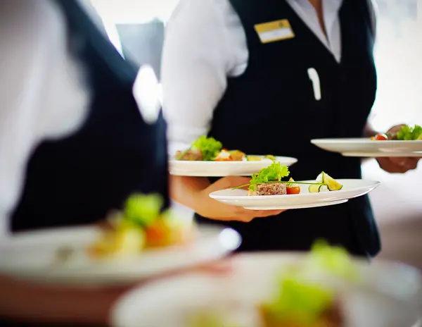 waiters servicing plates of colorful food