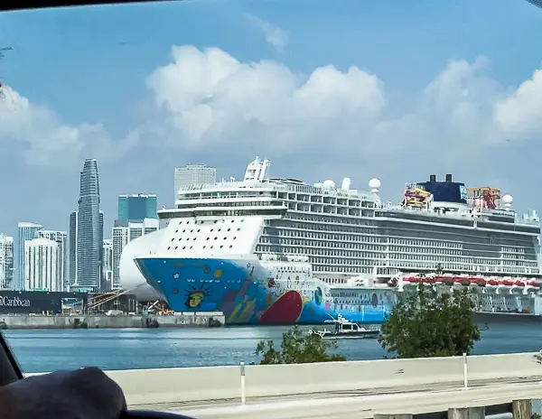 View of the Norwegian Breakaway cruise ship docked in Miami, seen from a car on embarkation day with the city skyline in the background.