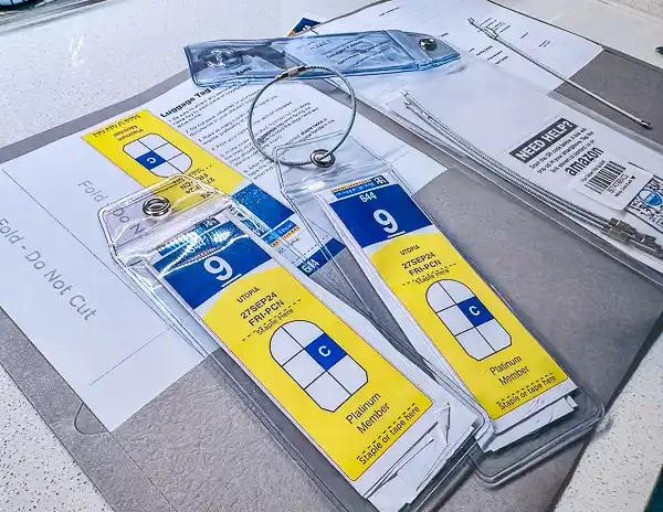 Cruise luggage tags in plastic holders with metal loops, prepared and ready to attach before embarkation day check-in.