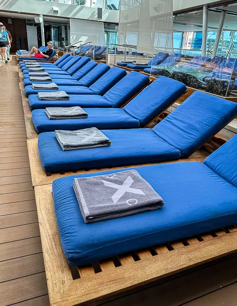 pools towels folded on available lounge chairs by indoor pool on cruise ship