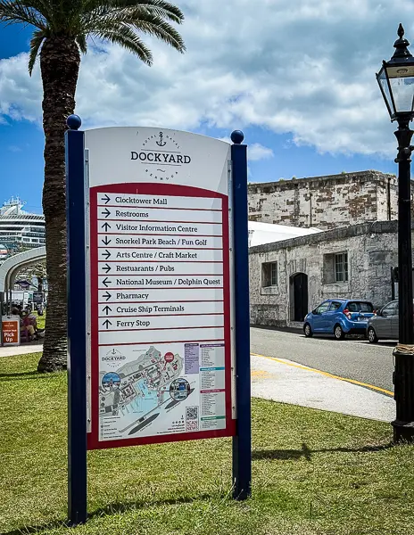 Directory sign at Royal Naval Dockyard in Bermuda showing directions to Clocktower Mall, visitor information, restaurants, ferry stop, and cruise ship terminals.