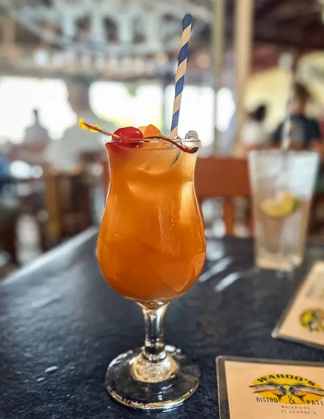 Rum Swizzle cocktail in Bermuda served in a hurricane glass with a cherry garnish.