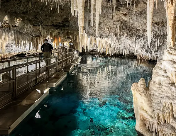 Crystal Cave in Bermuda with clear blue underground water, limestone formations, stalactites, and a walkway through the cave.