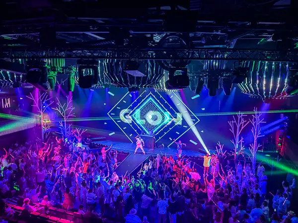 NCL Glow Party with passengers dancing under colorful lights