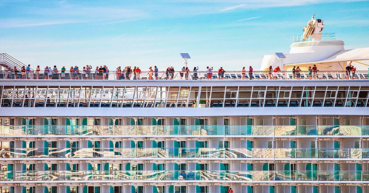 Cruise ship viewed from the side with passengers on deck, reflecting how cruise roll calls connect people on the same sailing