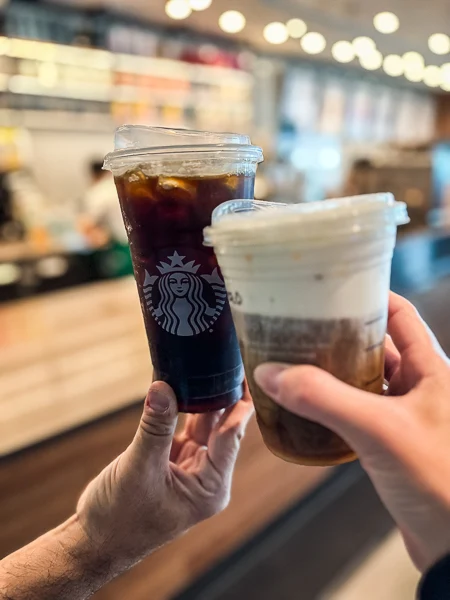 two cups of coffee clicking cheers at starbucks on a norwegian cruise ship
