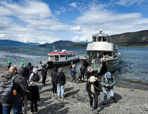 Cruisers disembarking excursion boats on a rocky beach near Davidson Glacier in Skagway, Alaska, during a cruise shore excursion with NCL sponsored tour.
