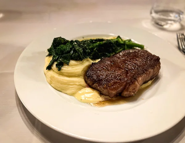 new york striploin, mash potatoe and green vegetables on a plate