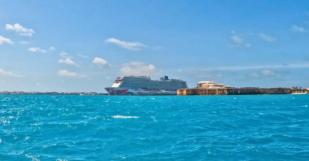 featured image: Bermuda cruise tips featured image with a Norwegian cruise ship docked at Royal Naval Dockyard, surrounded by bright turquoise water and blue skies.