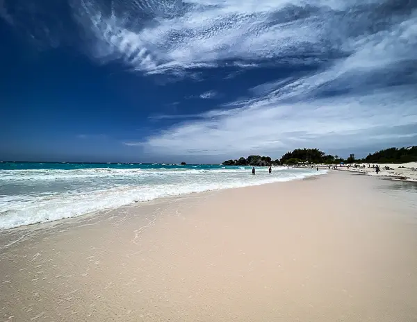 Wide view of Horseshoe Bay Beach in Bermuda with pale pink sand, turquoise water, and beachgoers along the shoreline.