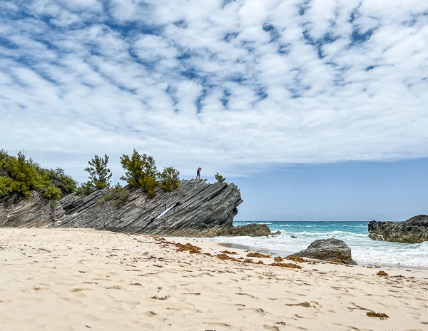 man standing in jagged rocks at beach