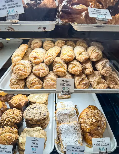 Display case at Merengue Bakery in Monrovia filled with Cuban pastries and other well known baked goods including queso crema, apple pecan strudel, and almond bear claws.