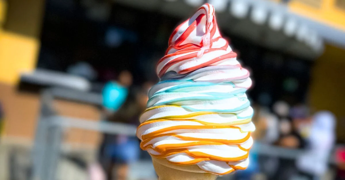 featured blog image features a swirl of soft-serve ice cream, with white and orange colors twisted around each other, held up against a blurred background as one of universal studios hollywood food and snacks