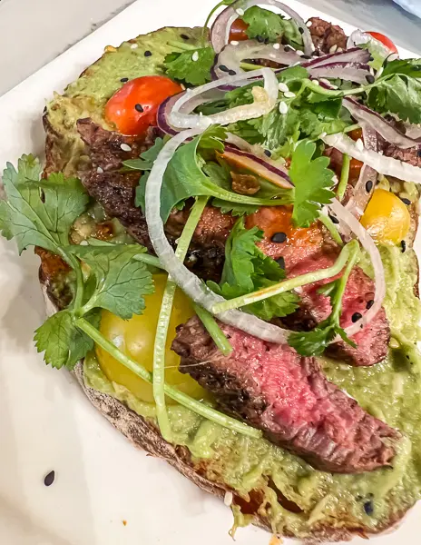 avocado toast with carne asada and tomatoes