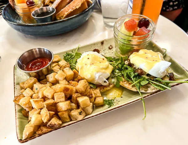 eggs benedict with potatoes and a side of fruit