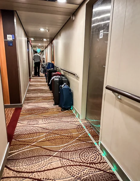 luggages lined up outside cabins in cruise ship corridor the night before disembarkation day