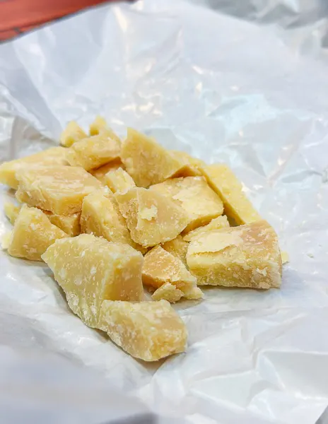 Chunks of aged Parmigiano Reggiano on wax paper—one of the local specialties to try on a day trip from Bologna to Parma.