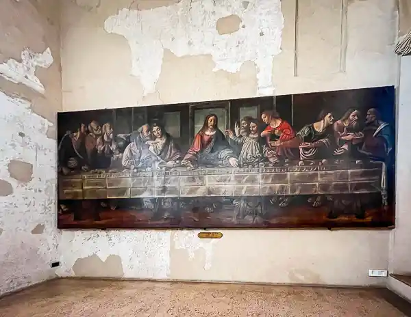 Painting of The Last Supper by Alessandro Araldi inside the entrance to the Chamber of St. Paul in Parma, Italy, displayed on a worn plaster wall