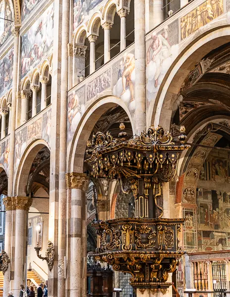 Ornate pulpit and archways with painted frescoes inside the Parma Cathedral in Italy