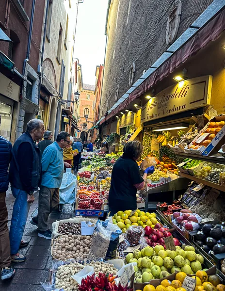 A vibrant produce market in Bologna’s Quadrilatero district, displaying colorful fruits, vegetables, and nuts.