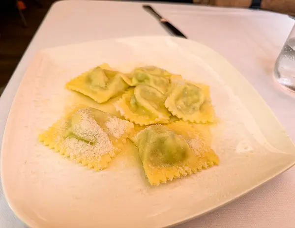 Fresh Tortelli d’Erbetta topped with grated Parmigiano Reggiano, served at La Forchetta in Parma, Italy