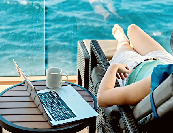 woman relaxing in cruise balcony with her laptop next to her