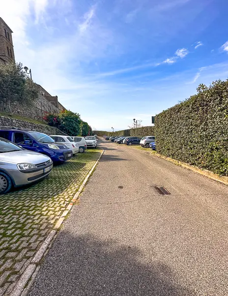 Parcheggio Pubblico, a public parking lot near Cortona’s historic center, with rows of parked cars and a bright blue sky above.