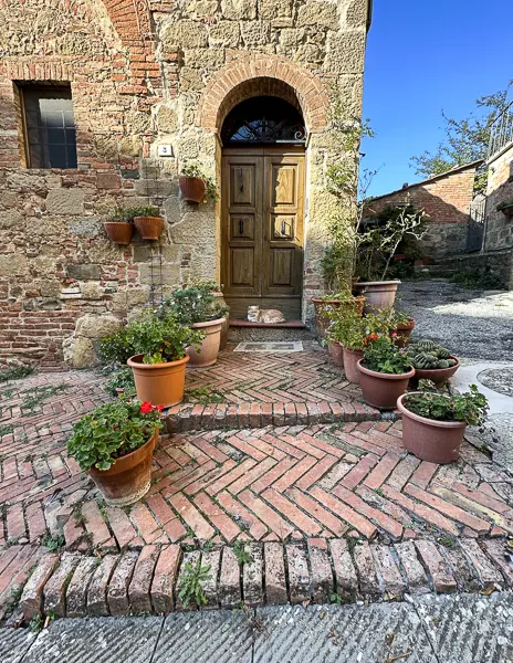 cat laying down in front of charming door in montechiello tuscany