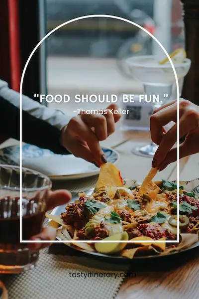 Food quote graphic featuring “Food should be fun” by Thomas Keller, over a photo of people sharing a plate of nachos at a restaurant, framed by a white arch