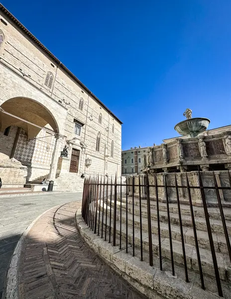 Side view of Fontana Maggiore and the Cathedral of San Lorenzo in Perugia, Italy, with a clear blue sky during one day in Perugia