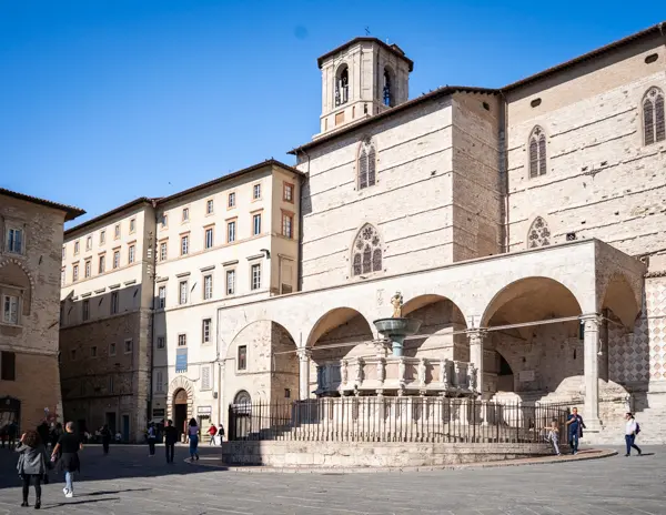 Fontana Maggiore in front of the Cathedral of San Lorenzo in Perugia, Italy, with people walking through Piazza IV Novembre during one day in Perugia