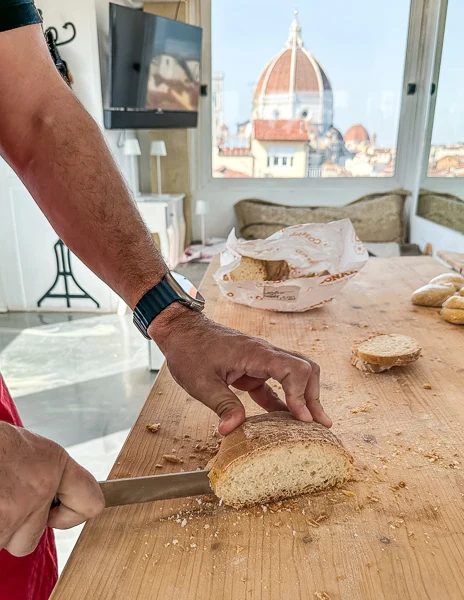 man cutting bread with the view of the duomo in the background at a cooking class in florence
