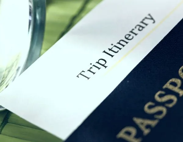 trip itinerary printed at the header of a piece of paper that's inside of a passport